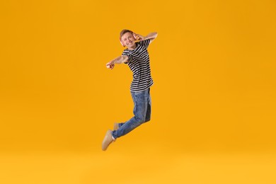 Photo of Happy young man with headphones jumping on orange background