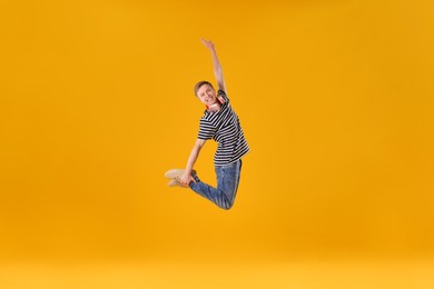 Photo of Happy young man with headphones jumping on orange background