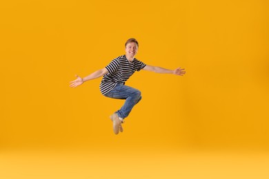 Photo of Happy young man jumping on orange background