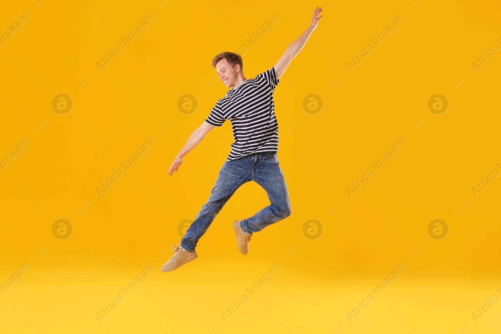 Happy young man jumping on orange background Photo of Happy young man jumping on orange background