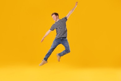 Photo of Happy young man jumping on orange background