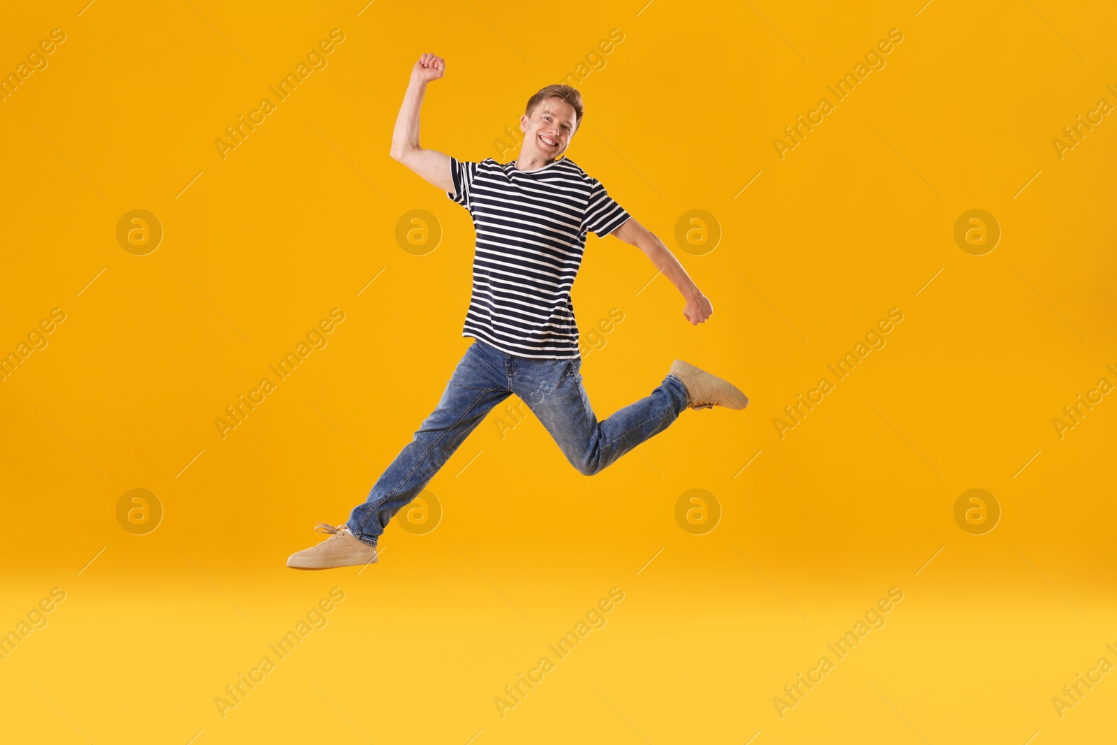 Happy young man jumping on orange background Photo of Happy young man jumping on orange background