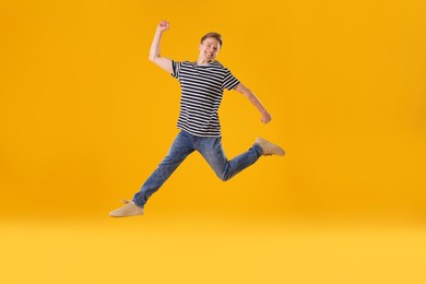 Photo of Happy young man jumping on orange background