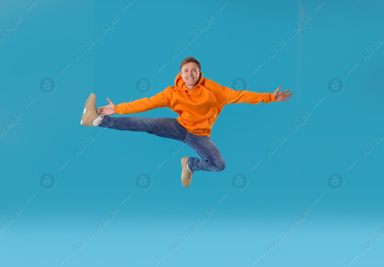 Happy young man jumping on light blue background Photo of Happy young man jumping on light blue background
