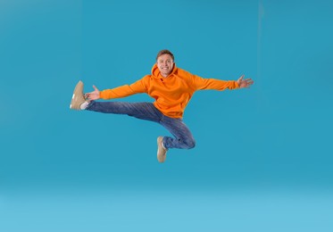 Photo of Happy young man jumping on light blue background