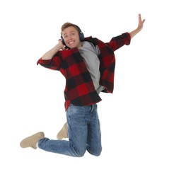 Photo of Portrait of happy young man with headphones jumping on white background