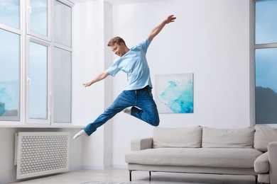 Photo of Portrait of happy young man jumping at home