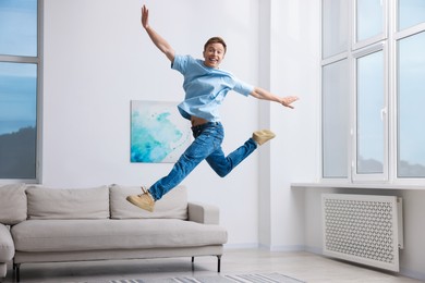 Photo of Portrait of happy young man jumping at home