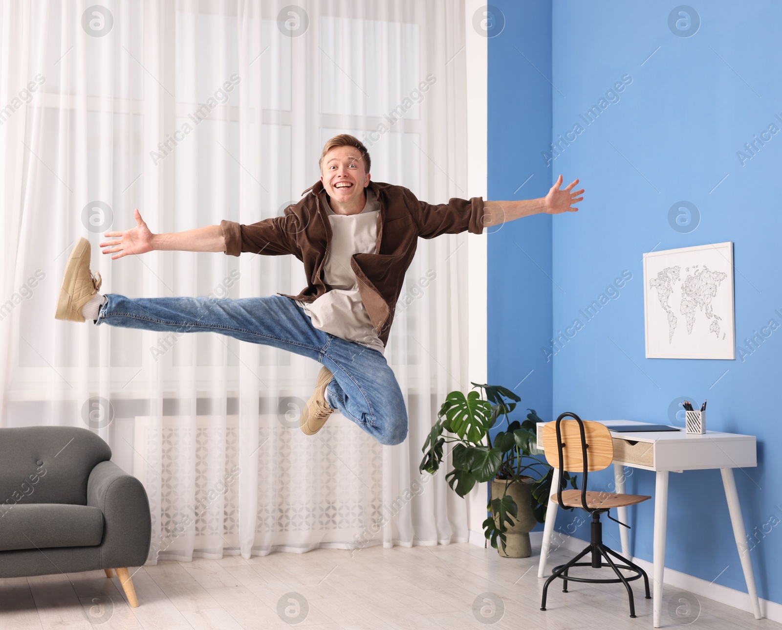 Portrait of happy young man jumping at home Photo of Portrait of happy young man jumping at home