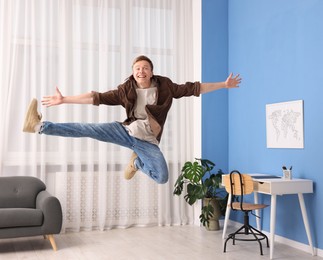 Photo of Portrait of happy young man jumping at home