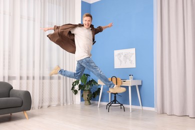 Photo of Portrait of happy young man jumping at home