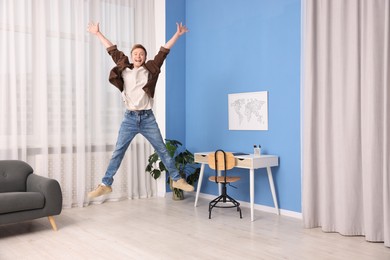Photo of Portrait of happy young man jumping at home