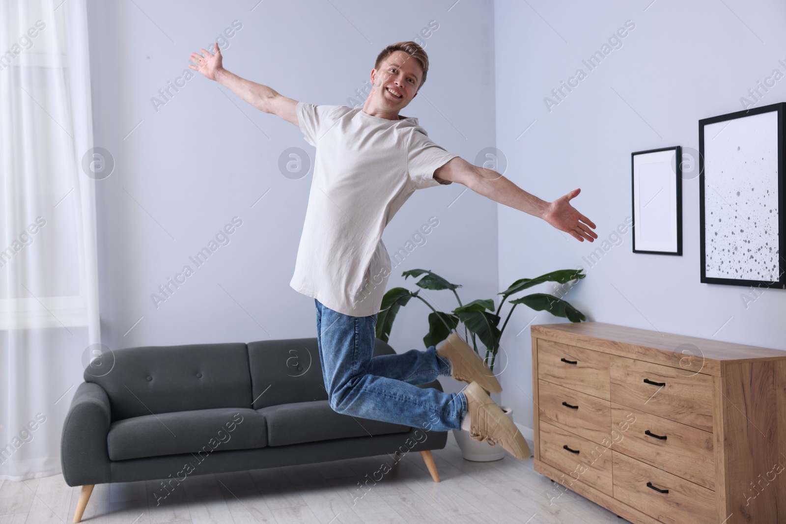 Portrait of happy young man jumping at home Photo of Portrait of happy young man jumping at home