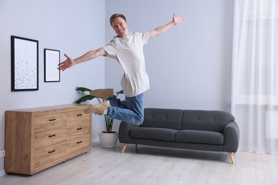 Photo of Portrait of happy young man jumping at home