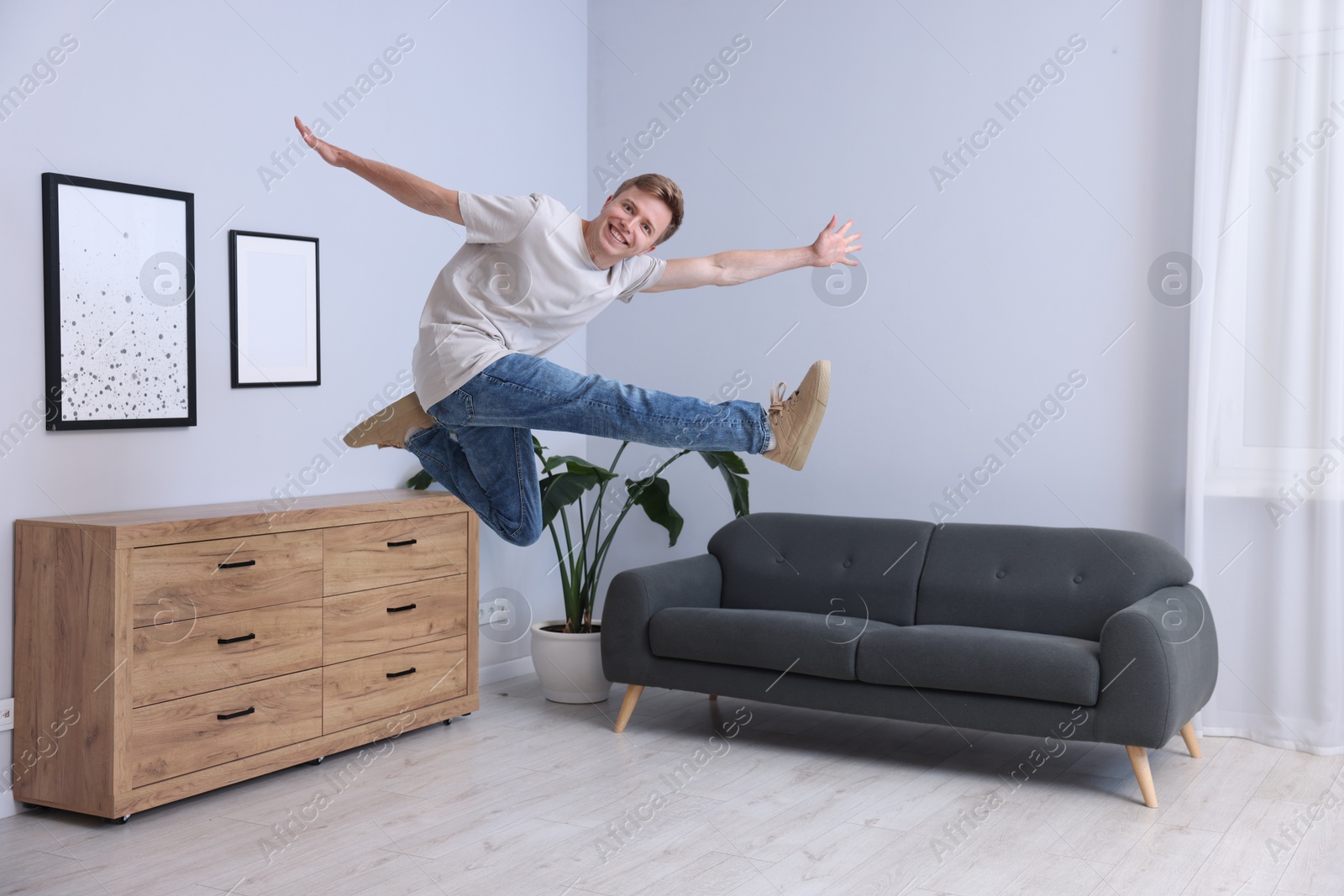 Portrait of happy young man jumping at home Photo of Portrait of happy young man jumping at home