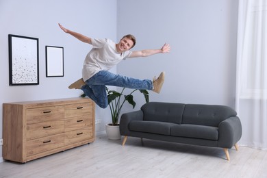 Photo of Portrait of happy young man jumping at home