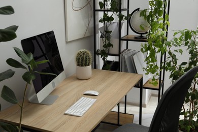Photo of Biophilic interior design. Stylish workplace with computer and houseplants in office