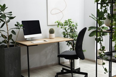 Photo of Biophilic interior design. Stylish workplace with computer and houseplants in office