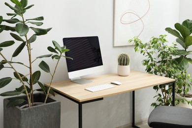 Photo of Biophilic interior design. Stylish workplace with computer and houseplants in office