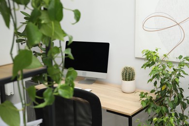 Photo of Biophilic interior design. Stylish workplace with computer and houseplants in office