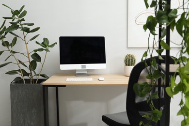 Photo of Biophilic interior design. Stylish workplace with computer and houseplants in office