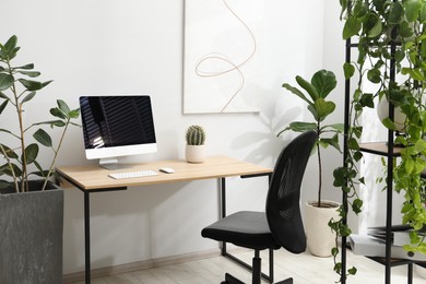 Photo of Biophilic interior design. Stylish workplace with computer and houseplants in office