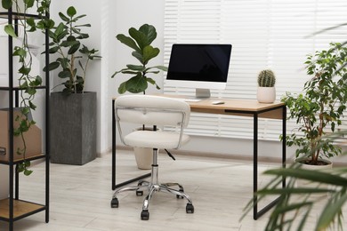 Photo of Biophilic interior design. Stylish workplace with computer and houseplants in office