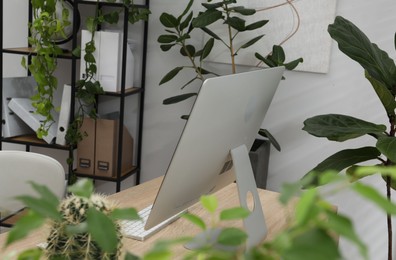Photo of Biophilic interior design. Stylish workplace with computer and houseplants in office