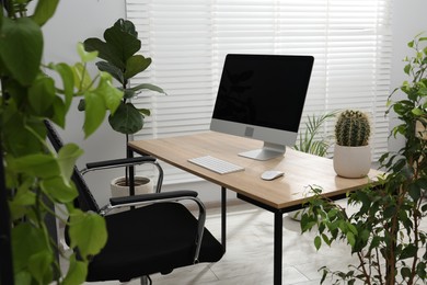 Photo of Biophilic interior design. Stylish workplace with computer and houseplants in office