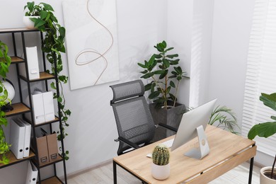 Photo of Biophilic interior design. Stylish workplace with computer and houseplants in office