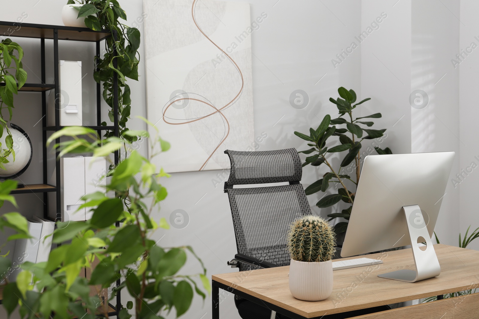 Photo of Biophilic interior design. Stylish workplace with computer and houseplants in office
