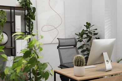 Photo of Biophilic interior design. Stylish workplace with computer and houseplants in office