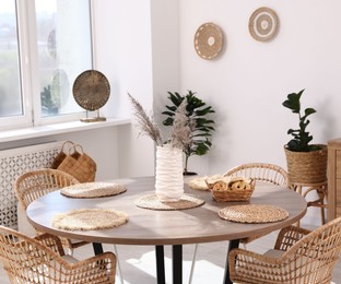 Photo of Stylish table with chairs and decor in dining room. Interior design