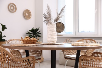 Photo of Stylish table with chairs and decor in dining room. Interior design