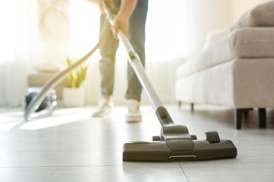 Photo of Man cleaning floor with vacuum cleaner at home, closeup