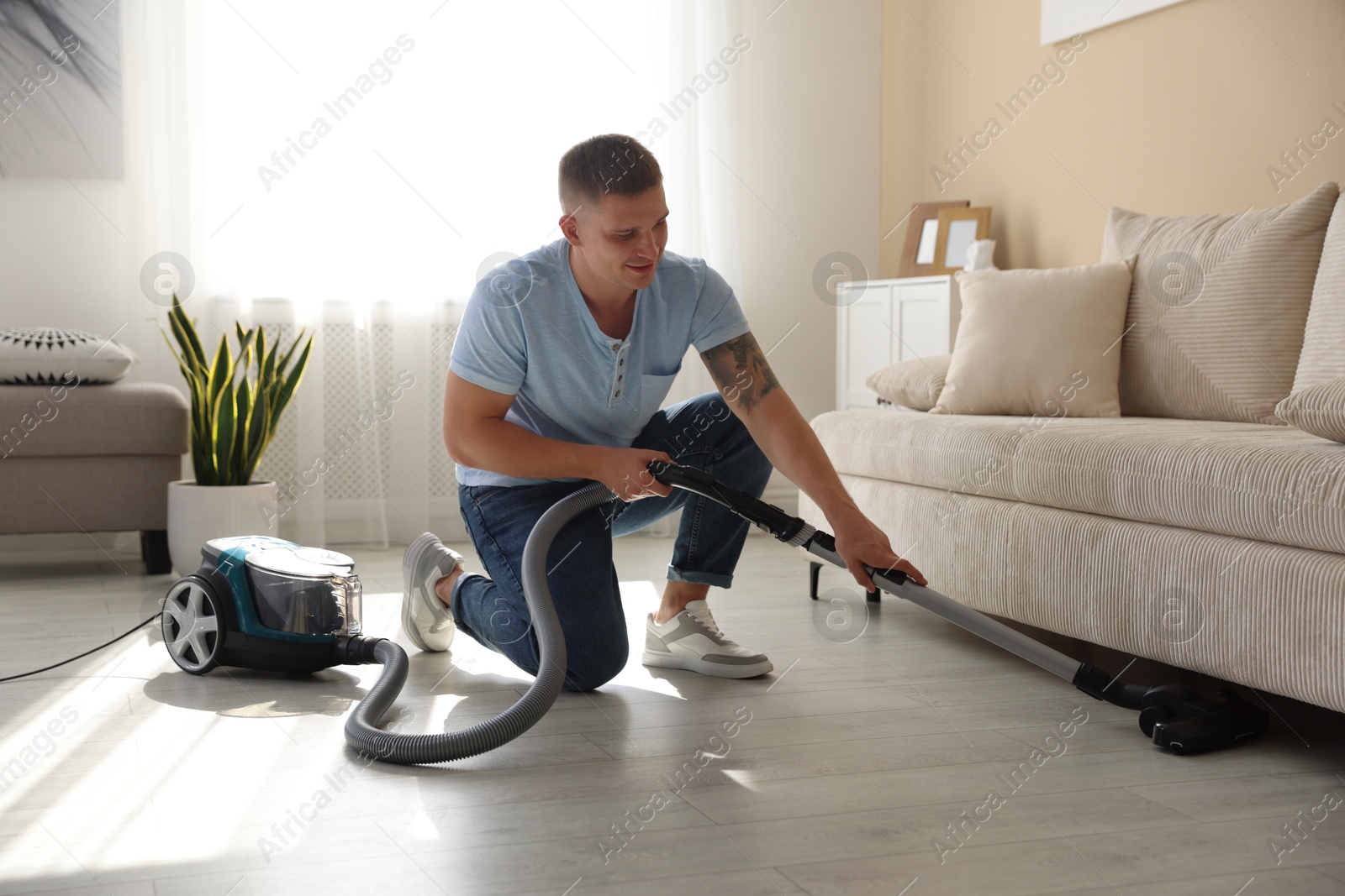 Man cleaning floor with vacuum cleaner at home Photo of Man cleaning floor with vacuum cleaner at home