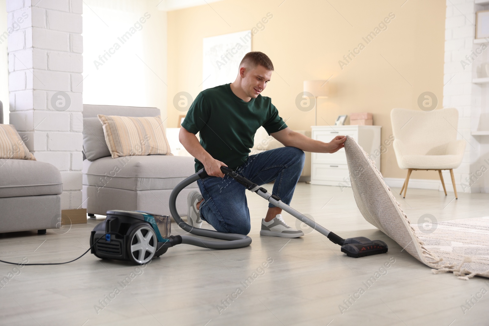 Man cleaning floor with vacuum cleaner at home Photo of Man cleaning floor with vacuum cleaner at home