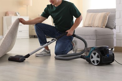 Photo of Man cleaning floor with vacuum cleaner at home, closeup