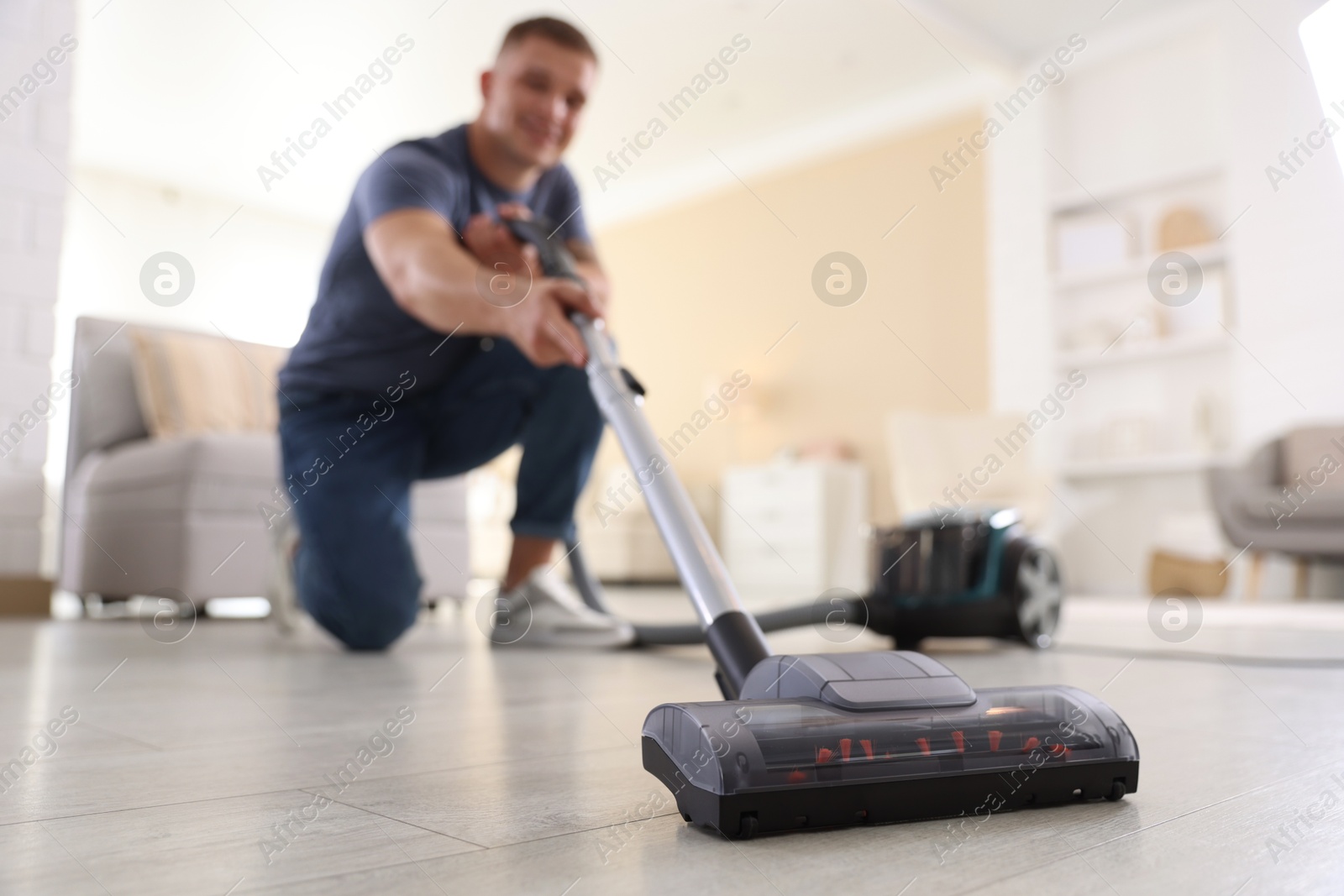 Man cleaning floor with vacuum cleaner at home, low angle view Photo of Man cleaning floor with vacuum cleaner at home, low angle view