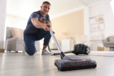 Photo of Man cleaning floor with vacuum cleaner at home, low angle view