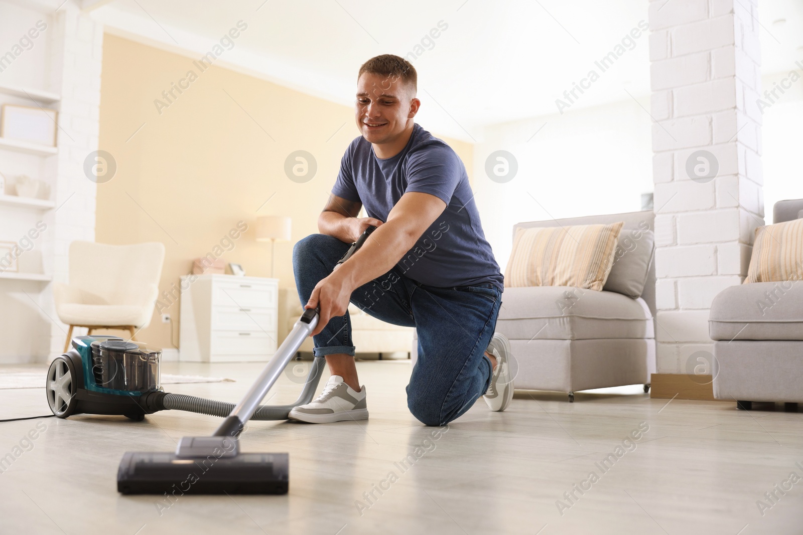 Man cleaning floor with vacuum cleaner at home, low angle view Photo of Man cleaning floor with vacuum cleaner at home, low angle view