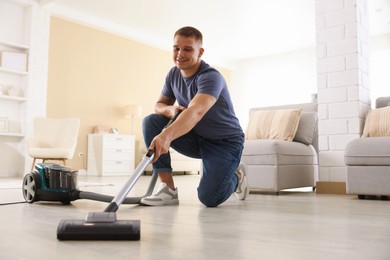 Photo of Man cleaning floor with vacuum cleaner at home, low angle view