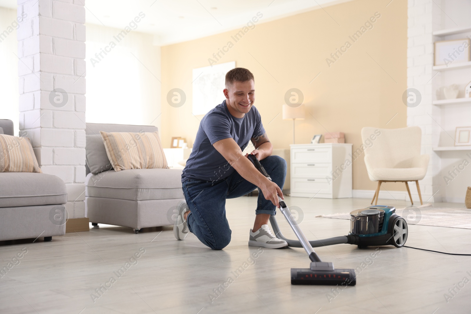 Man cleaning floor with vacuum cleaner at home Photo of Man cleaning floor with vacuum cleaner at home