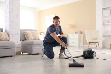 Photo of Man cleaning floor with vacuum cleaner at home