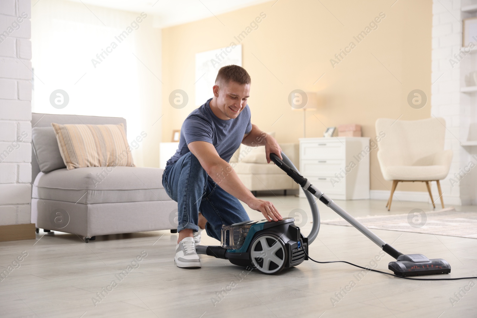 Happy man with vacuum cleaner at home Photo of Happy man with vacuum cleaner at home