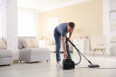 Photo of Happy man with vacuum cleaner at home