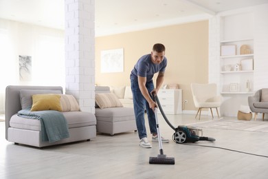 Photo of Man cleaning floor with vacuum cleaner at home
