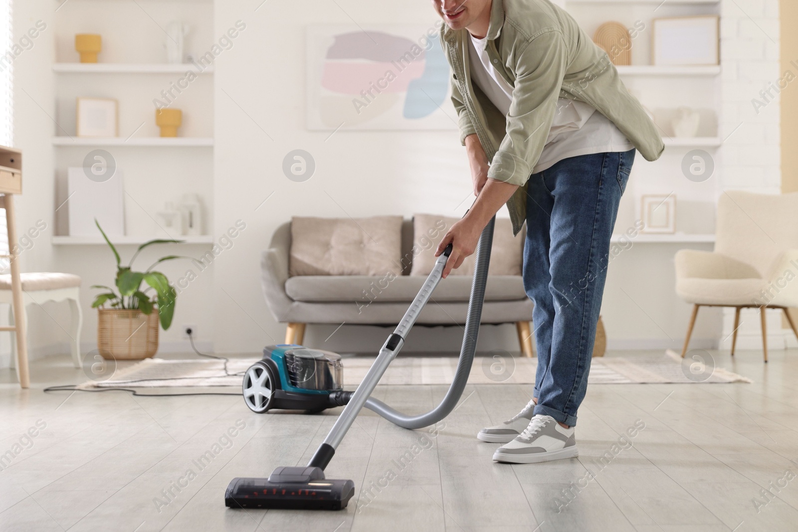 Man cleaning floor with vacuum cleaner at home, closeup Photo of Man cleaning floor with vacuum cleaner at home, closeup