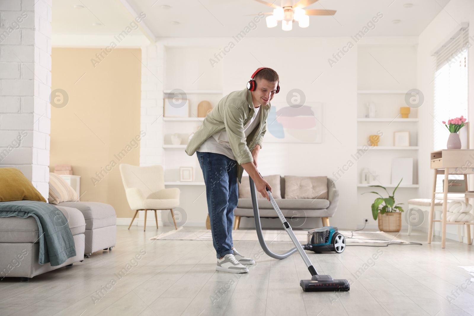 Man in headphones cleaning floor with vacuum cleaner at home Photo of Man in headphones cleaning floor with vacuum cleaner at home