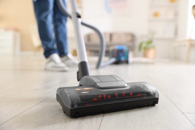 Photo of Man cleaning floor with vacuum cleaner at home, closeup